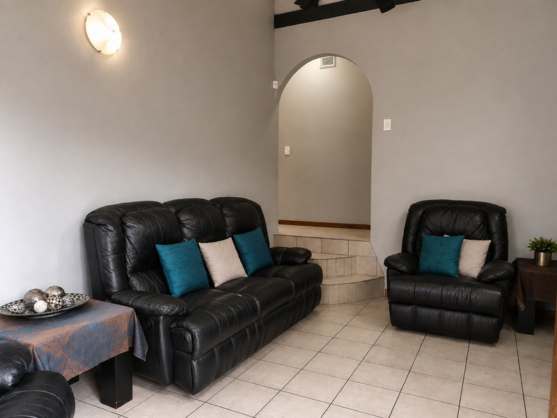 A living room featuring tiled flooring, an arched doorway leading to an elevated area, and neutral wall finishes.