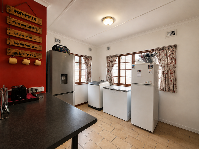 A functional laundry area featuring tiled flooring, ample space for appliances, and a practical countertop workspace.