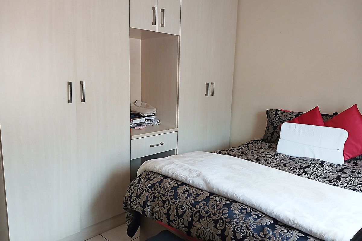 A bedroom featuring light-toned built-in cupboards with an integrated vanity unit, providing ample storage and functional space.