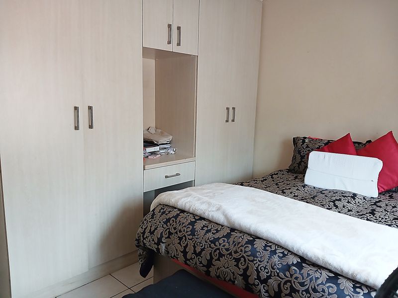 A bedroom featuring light-toned built-in cupboards with an integrated vanity unit, providing ample storage and functional space.