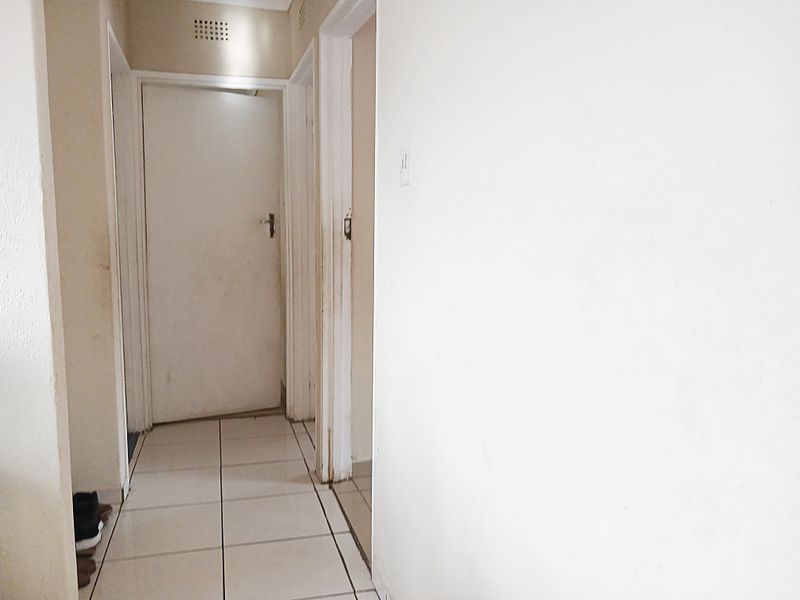 A functional hallway featuring tiled flooring and multiple internal doors, providing access to various rooms within the home.