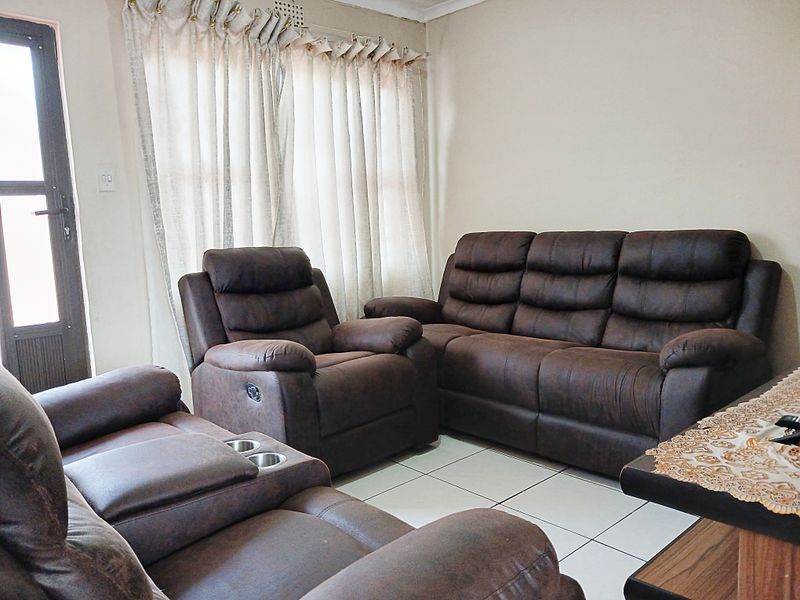 A living room featuring tiled flooring, neutral walls, and a glass panel door leading to the exterior.