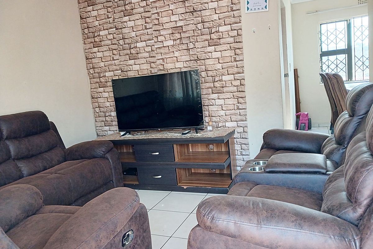 Living room featuring a faux stone accent wall, ceramic tiled flooring, and security bars on the window.
