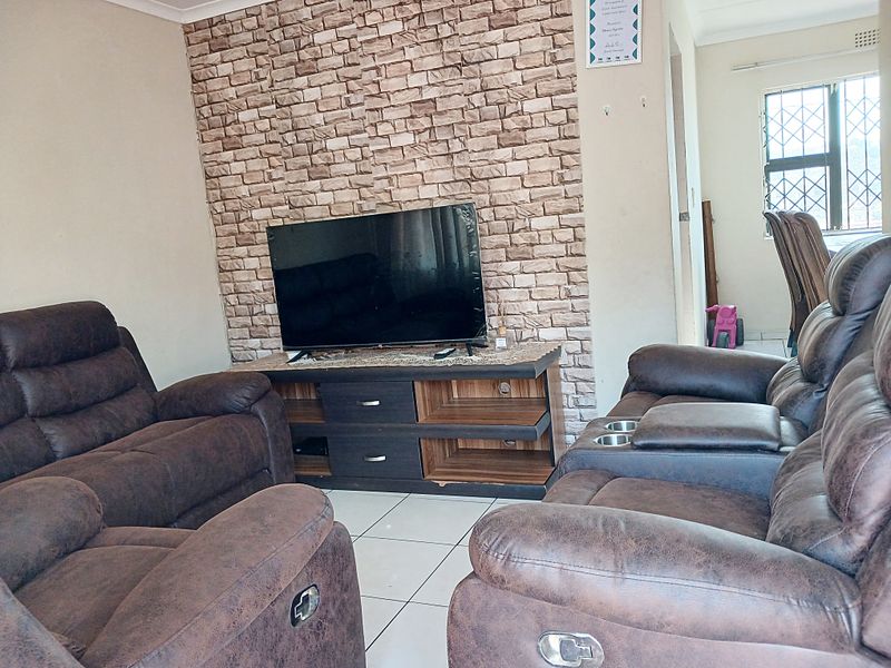 Living room featuring a faux stone accent wall, ceramic tiled flooring, and security bars on the window.