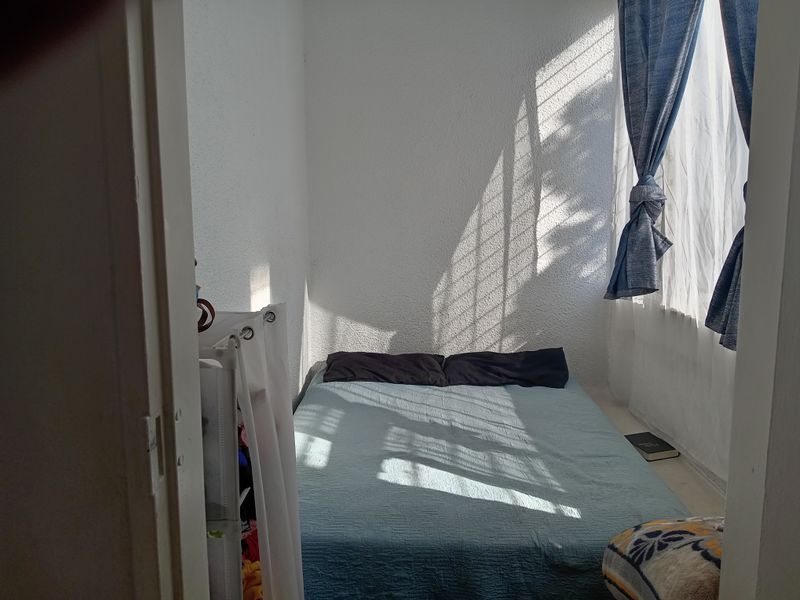 A compact bedroom featuring a window with natural light, providing a functional space for rest.
