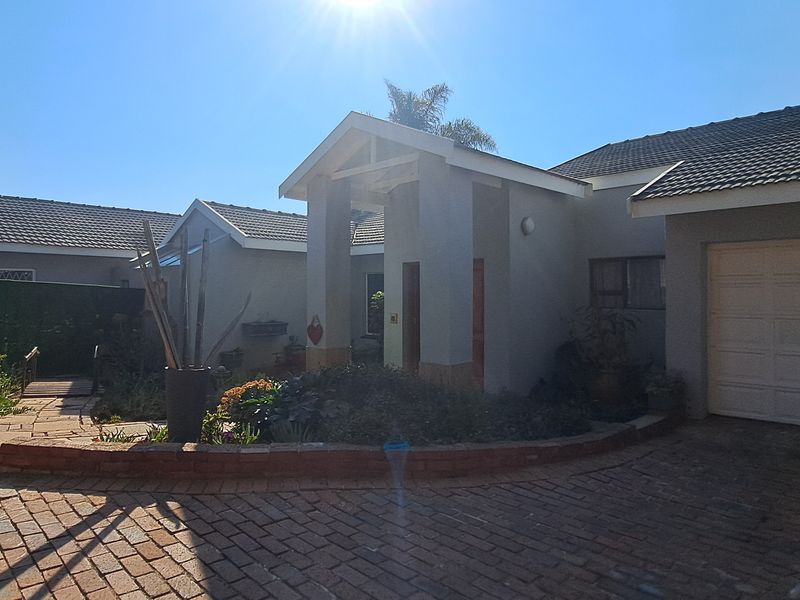 Front elevation of a residential house featuring a brick paved driveway, covered entrance, and integrated garage.