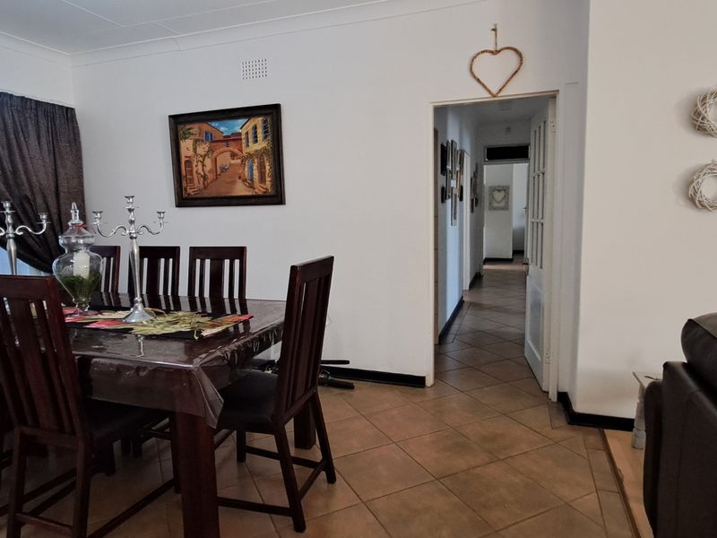 Open plan dining area featuring tiled flooring and access to a hallway, providing a functional layout for family living.