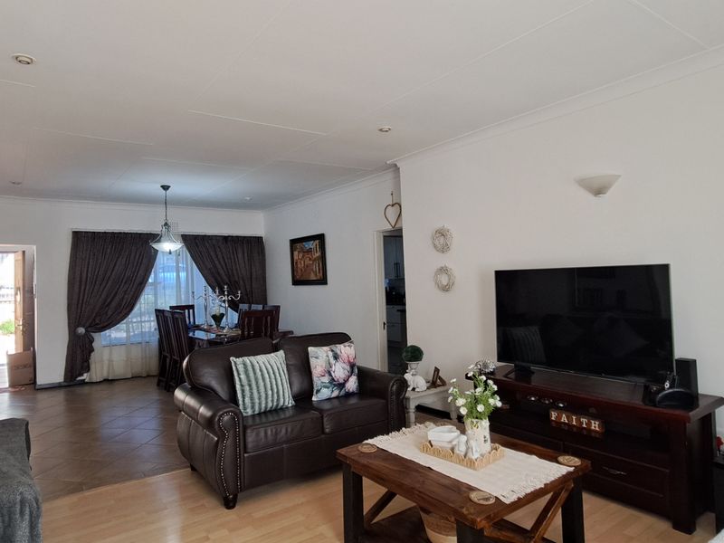 Open-plan living and dining area featuring a combination of laminate and tiled flooring with recessed ceiling lighting and coved cornicing.