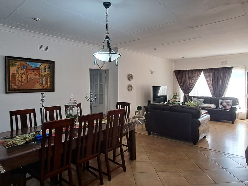 Spacious open-plan living and dining area featuring a mix of tiled and laminate flooring with neutral walls and integrated lighting.