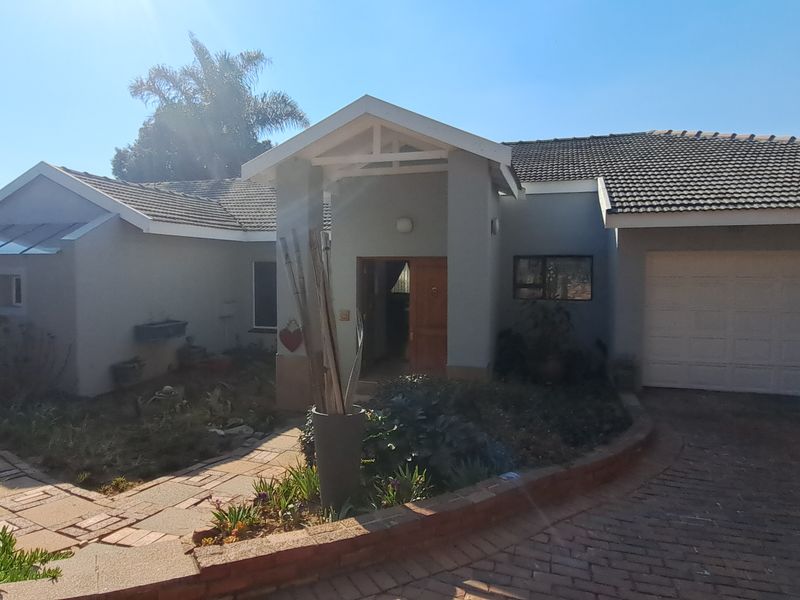 Front elevation of a single-story house featuring a tiled roof, double garage, paved driveway, and a stone pathway leading to the main entrance.