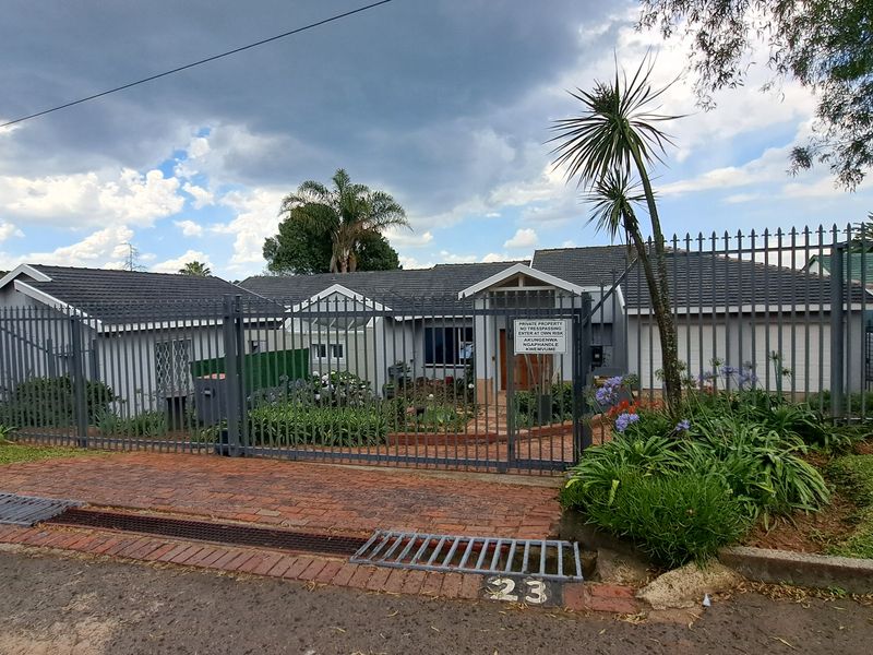 Front elevation of a residential property featuring a tiled roof, double garage, and secure metal perimeter fencing with a gated entrance.