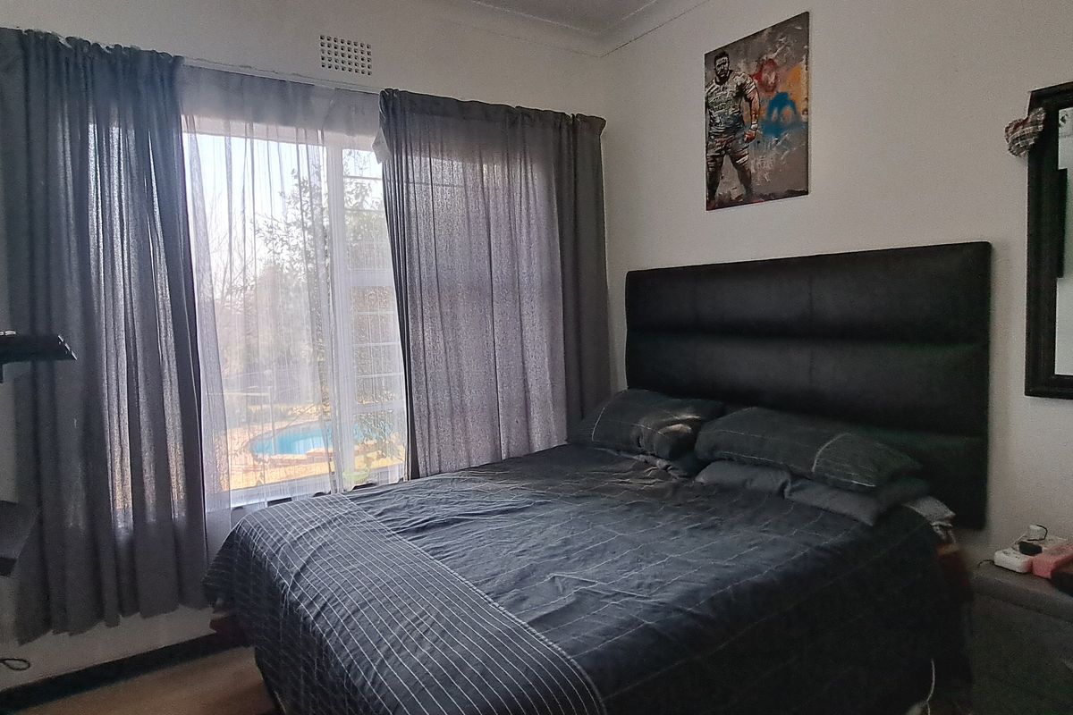 A functional bedroom featuring a sliding window with views of the pool area, cove cornicing, and wall-mounted shelving units.