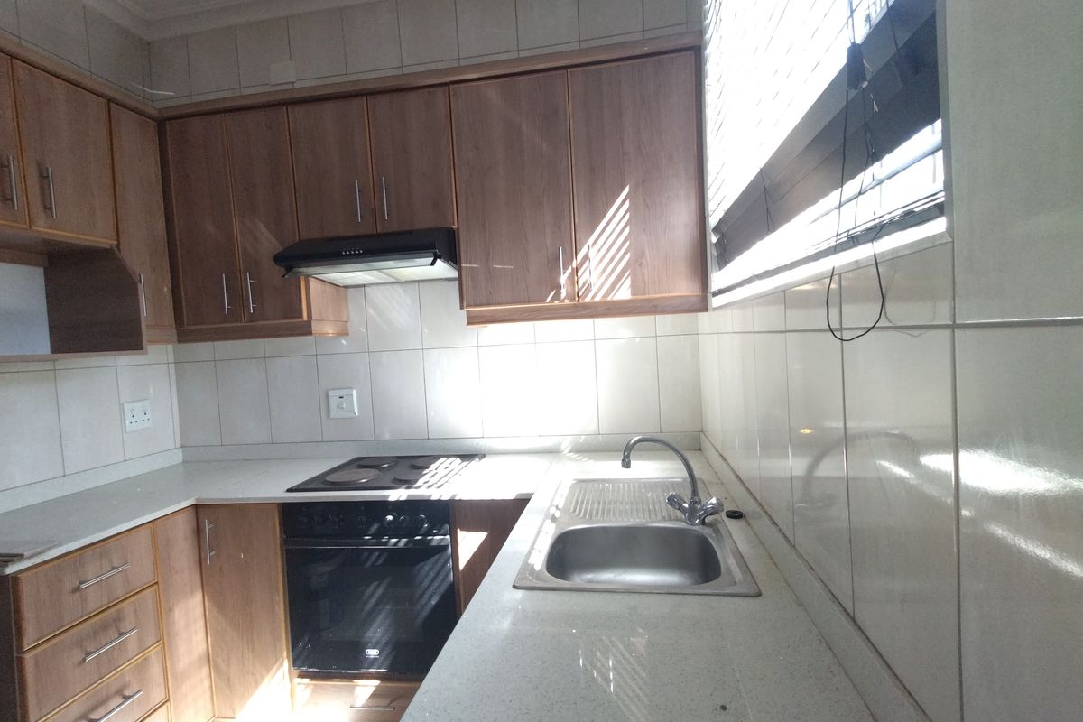 A functional kitchen featuring laminate cabinetry, stone countertops, a built-in oven with hob, and a stainless steel sink with tiled backsplash.