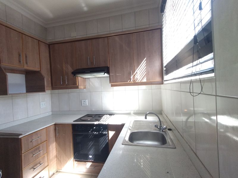 A functional kitchen featuring laminate cabinetry, stone countertops, a built-in oven with hob, and a stainless steel sink with tiled backsplash.