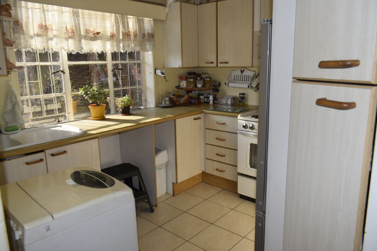 A functional kitchen featuring laminate cabinetry, tiled flooring, and a freestanding stove, offering a practical layout with natural light from the window.
