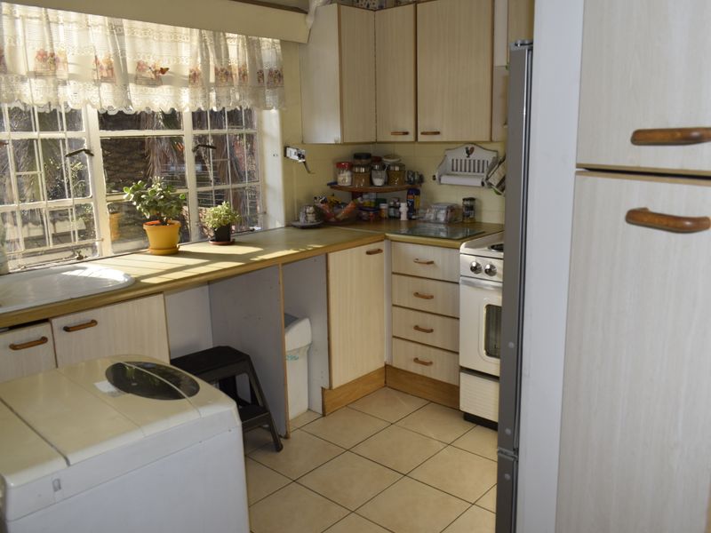 A functional kitchen featuring laminate cabinetry, tiled flooring, and a freestanding stove, offering a practical layout with natural light from the window.