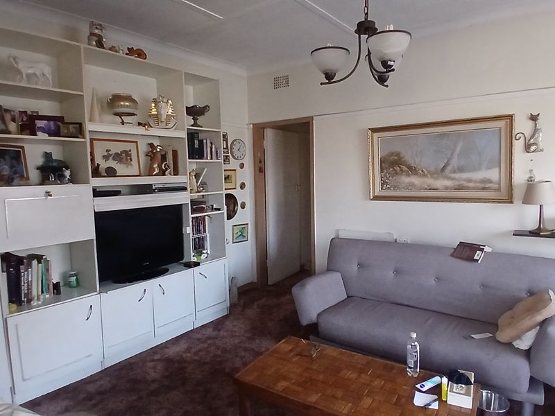 A living room featuring a large built-in shelving unit and traditional picture rails, offering a functional space with potential for modernization.