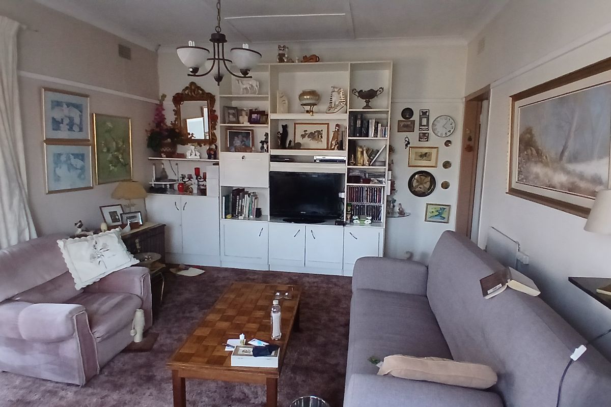 A living room featuring a large built-in shelving unit and traditional picture rails, offering a functional space with potential for modernization.