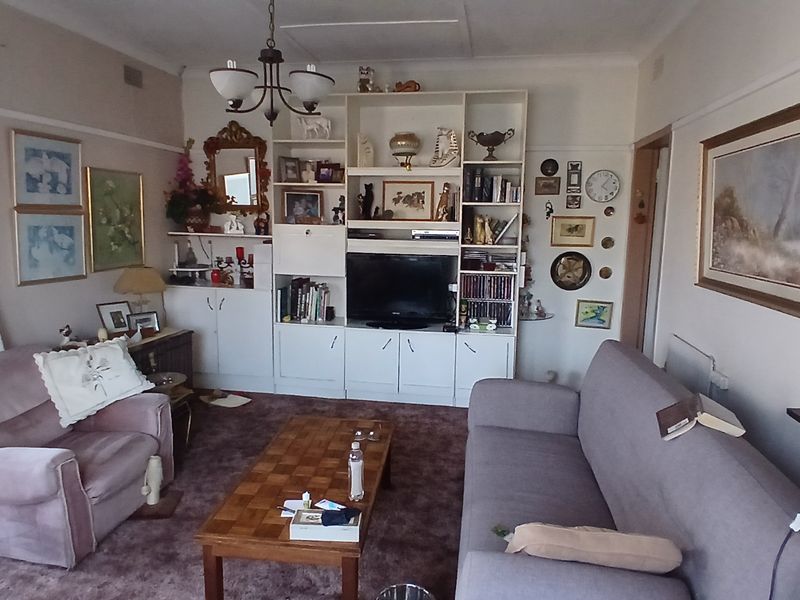 A living room featuring a large built-in shelving unit and traditional picture rails, offering a functional space with potential for modernization.