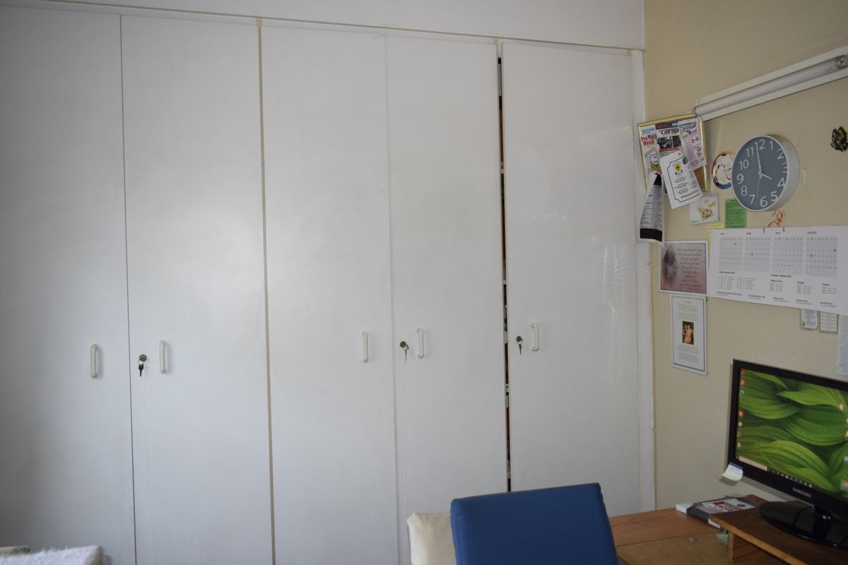 A bedroom featuring white built-in cupboards with integrated handles and locks, providing ample storage space.