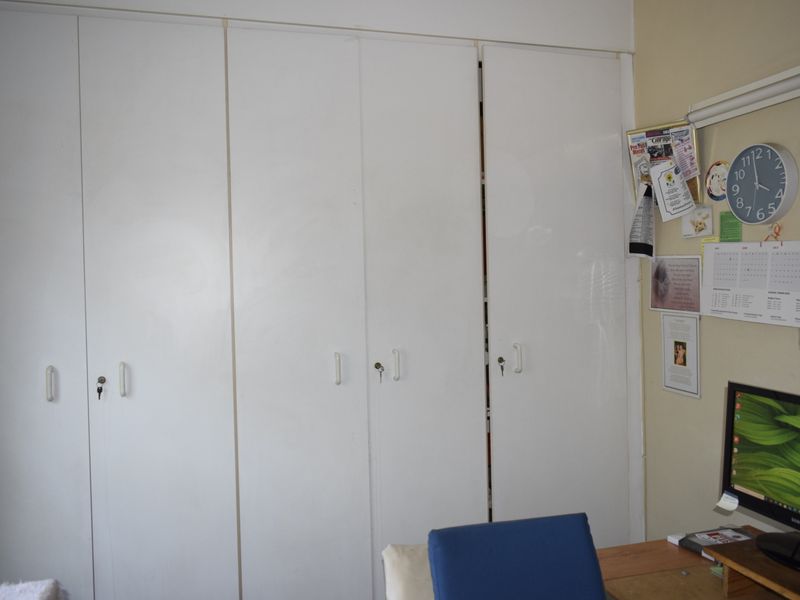 A bedroom featuring white built-in cupboards with integrated handles and locks, providing ample storage space.