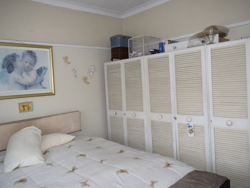 A bedroom featuring built-in cupboards with louvered doors and decorative coving.