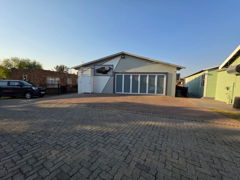 Front exterior view of the property featuring a paved driveway, modern bi-fold glass doors, and secure perimeter fencing.