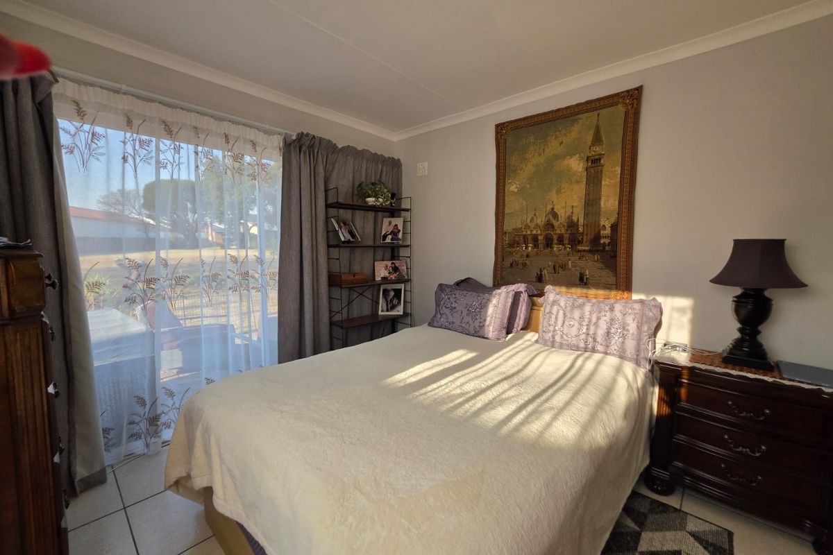 A well-lit bedroom featuring tiled flooring and a large sliding glass door providing natural light and access to the exterior.