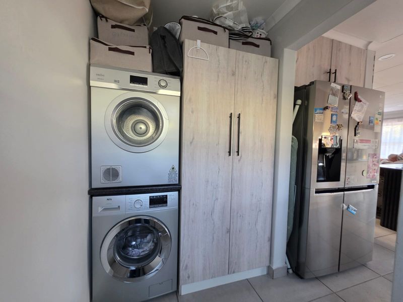 A functional laundry area featuring stacked laundry appliances and built-in cabinetry, seamlessly integrated into the home's utility space.