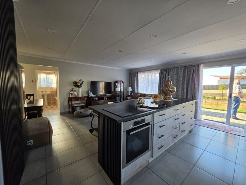 Spacious open-plan living area featuring a modern kitchen island with built-in oven, tiled flooring, and large sliding doors leading to the exterior.