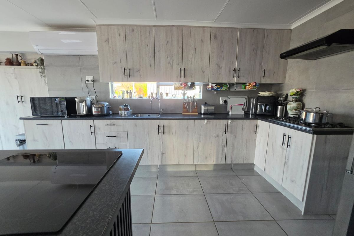 Modern kitchen featuring light wood-grain cabinetry, dark countertops, tiled flooring, integrated gas hob, extractor fan, and a functional layout with ample storage.