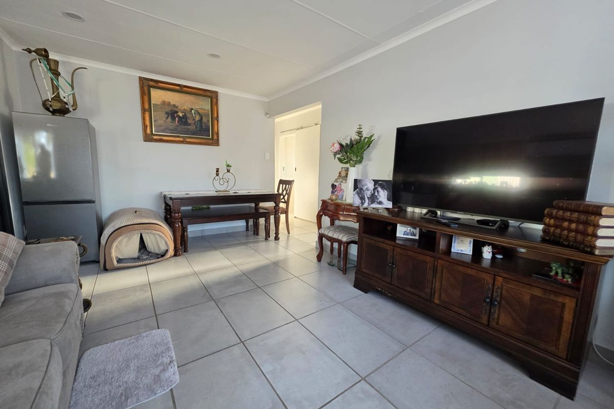 A spacious living area featuring neutral tiled flooring and recessed ceiling lighting, providing a functional and well-lit space for relaxation.