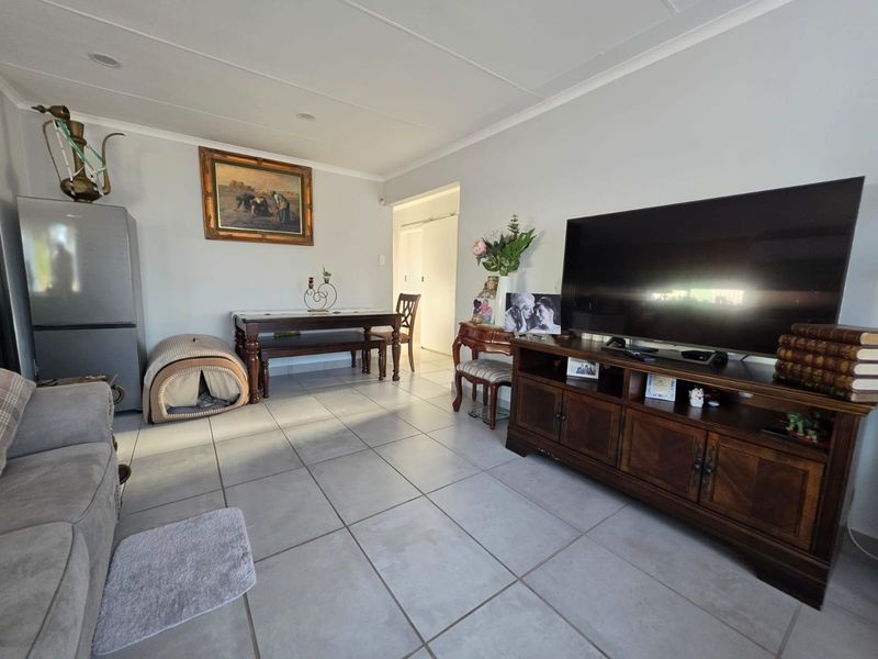 A spacious living area featuring neutral tiled flooring and recessed ceiling lighting, providing a functional and well-lit space for relaxation.