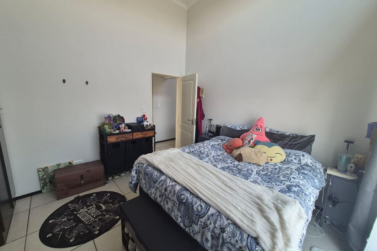 A bedroom featuring tiled flooring and high ceilings, providing a functional space with potential for cosmetic updates.