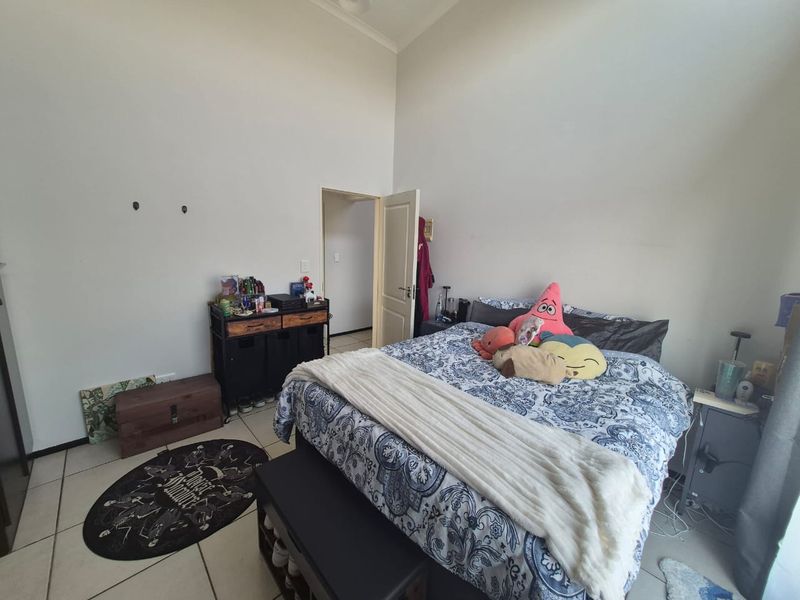 A bedroom featuring tiled flooring and high ceilings, providing a functional space with potential for cosmetic updates.