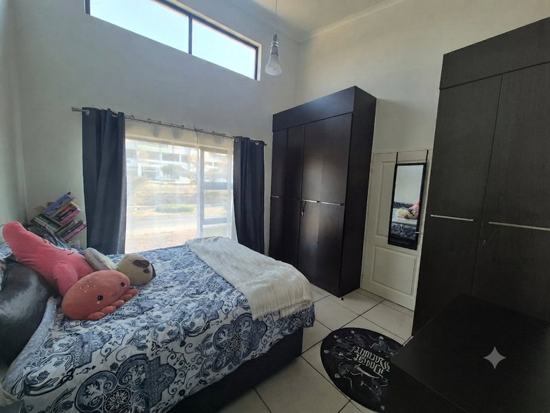 A bedroom featuring high ceilings with a clerestory window, tiled flooring, and dark wood built-in cupboards.