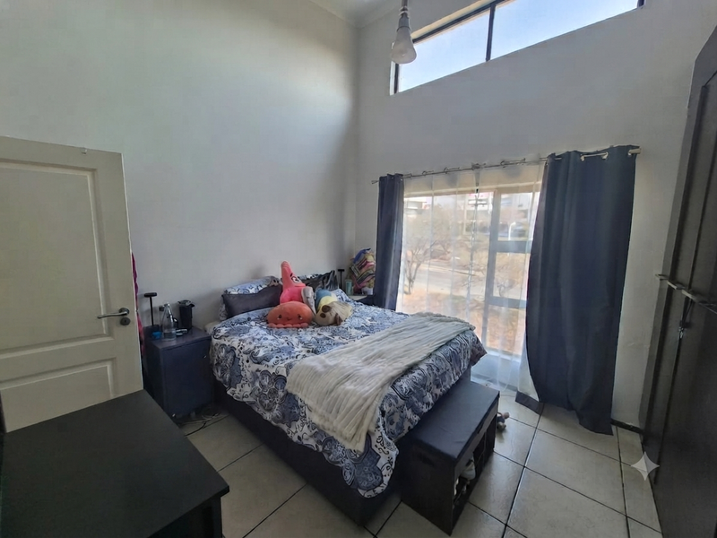 A bedroom featuring tiled flooring, a high-level clerestory window for natural light, and a built-in wardrobe.