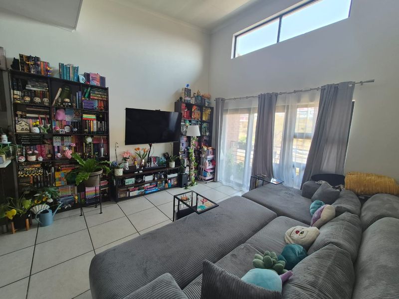 Spacious living room featuring high ceilings, large clerestory windows for natural light, and sliding glass doors leading to an outdoor area.
