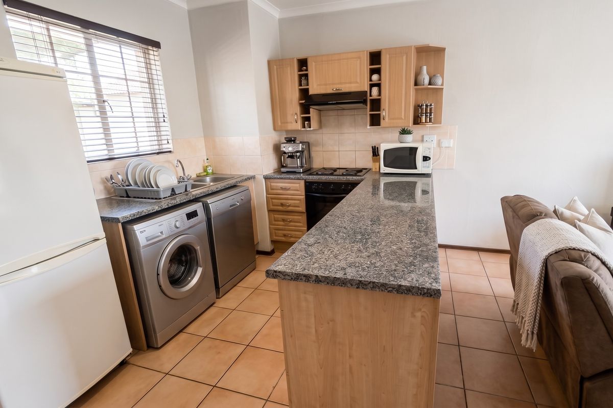 A functional kitchen featuring wooden cabinetry, granite countertops, a tiled backsplash, and integrated appliances, seamlessly connected to the living area.