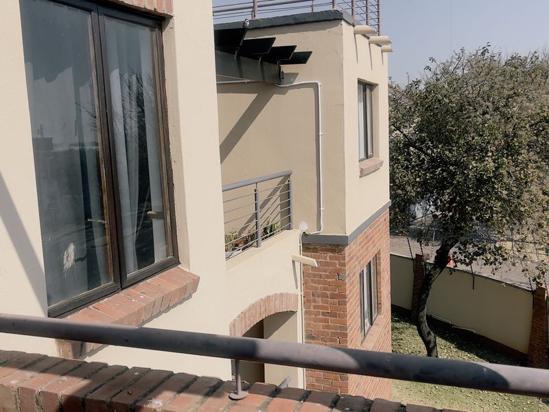 A view from a balcony overlooking the exterior facade of the apartment building, featuring brick detailing and metal railings.
