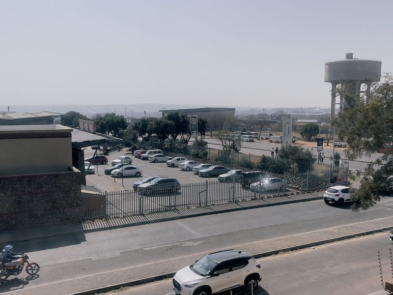 An elevated view overlooking a local street, parking area, and surrounding infrastructure including a prominent water tower.