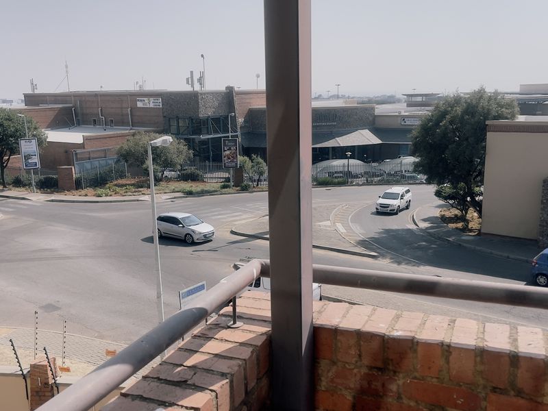 A balcony view overlooking a street intersection and nearby commercial buildings.