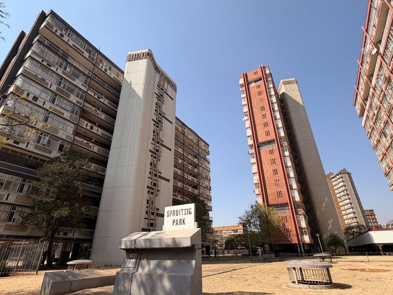 Exterior view of Spruitsig Park residential apartment complex featuring multi-story buildings with brick and concrete facades and a central courtyard area.