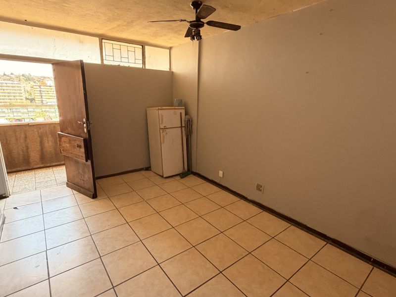 An empty living area featuring tiled flooring, a ceiling fan, and direct access to an outdoor balcony space.