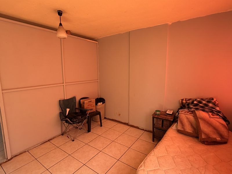 A bedroom featuring tiled flooring and a partition wall, currently in need of cosmetic updates and improved lighting.
