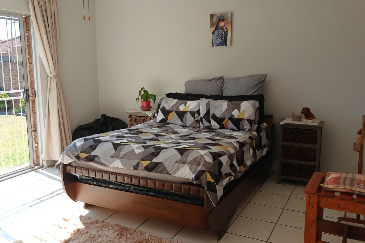A bedroom featuring tiled flooring and a sliding glass door with a security gate providing direct access to the garden.