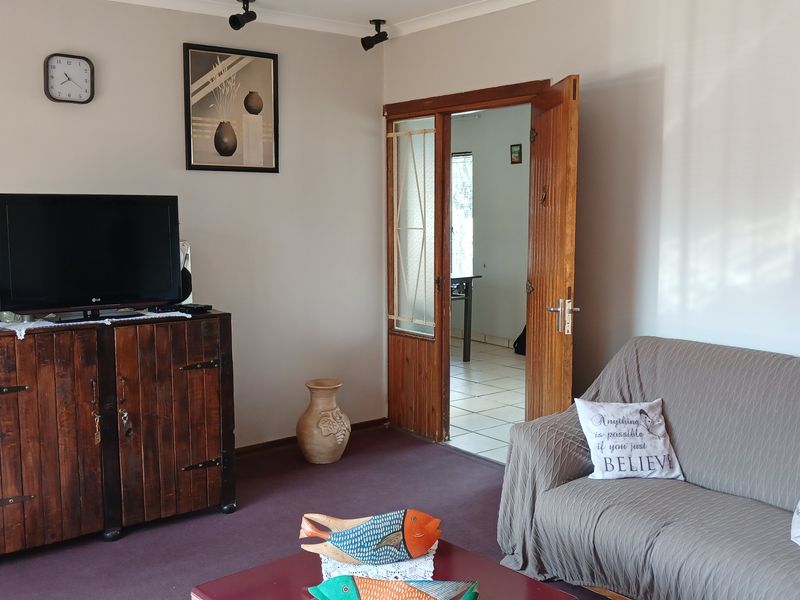 A living room featuring carpeted flooring, track lighting, and a wooden door frame leading to an adjacent space.