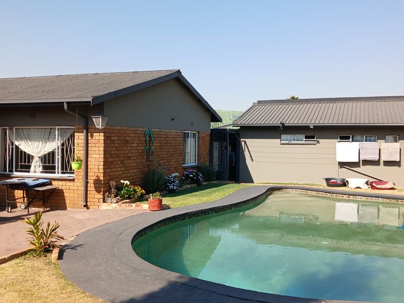 Outdoor pool area featuring a swimming pool with brick paving and a view of the rear building facade.