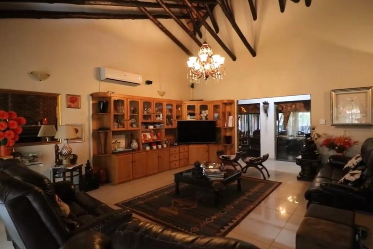 Spacious living room featuring a high vaulted ceiling with exposed timber rafters, built-in wooden cabinetry, and tiled flooring.