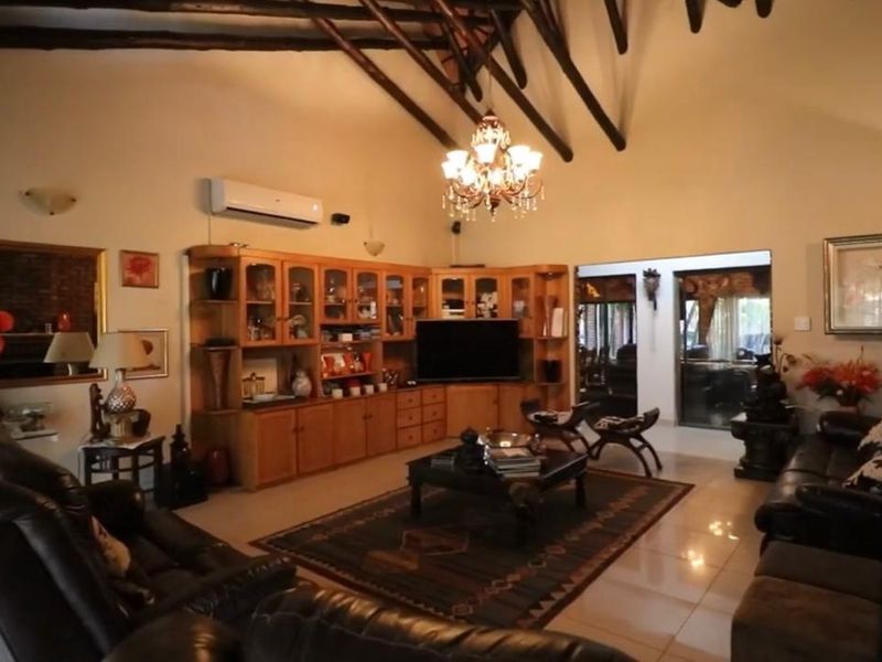 Spacious living room featuring a high vaulted ceiling with exposed timber rafters, built-in wooden cabinetry, and tiled flooring.